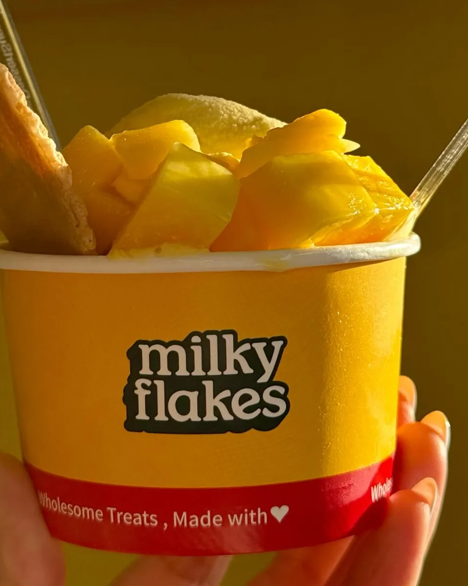 Alphonso mango soft scoop topped with fresh mango and a waffle cookie in a milky flakes cup.
