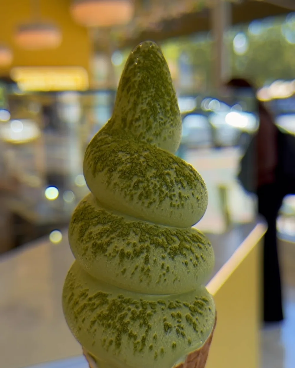 Organic matcha soft serve dusted with matcha powder, inside the shop.