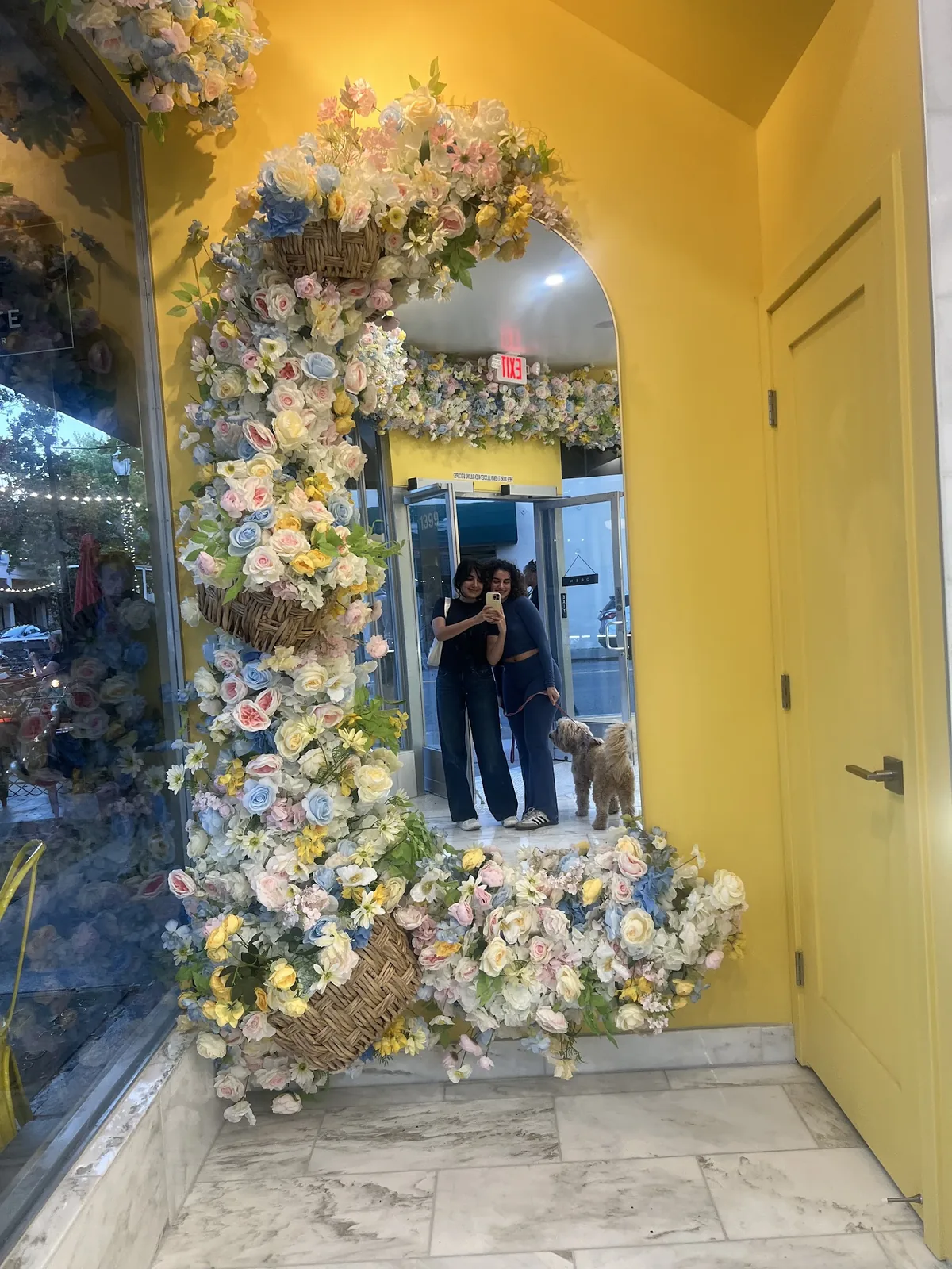 A floral arch framing a mirror against a yellow wall inside the shop.